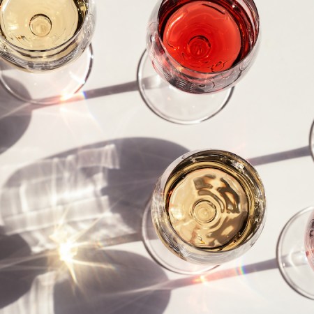 Red, rose and white wine top view in sunlight. Assorted wine in glass. Dark shadows