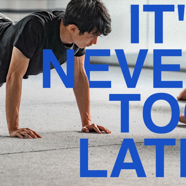 Person practicing Pilates on all fours during a class, with large blue overlay text that reads “It’s Never Too Late”