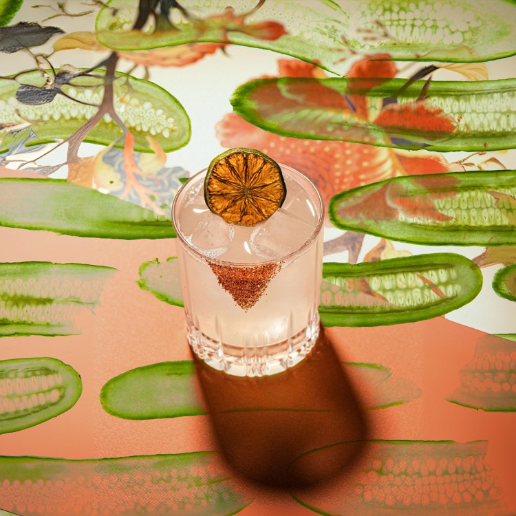A margarita on a table covered with graphic images of pickles